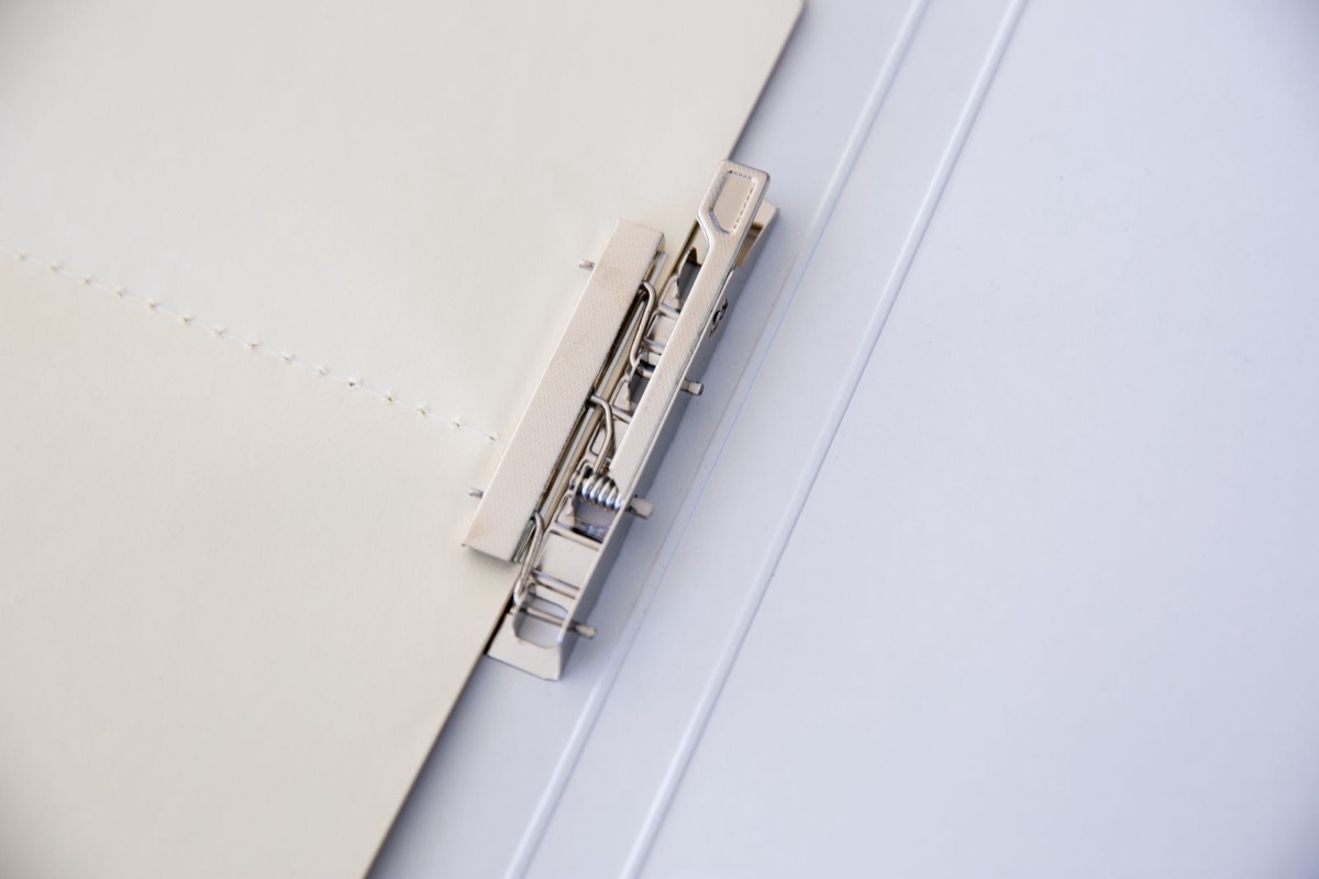 Close-up of the metal clip mechanism inside an open ring binder or document folder