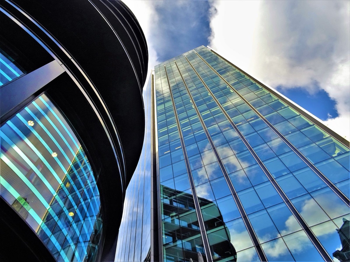 The glass facade of a modern office building seen from the street in daylight
